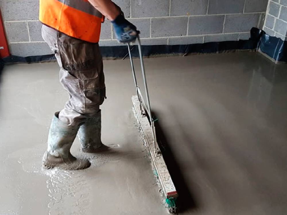 A Marton Flooring Services fitter levelling a fresh floor screed